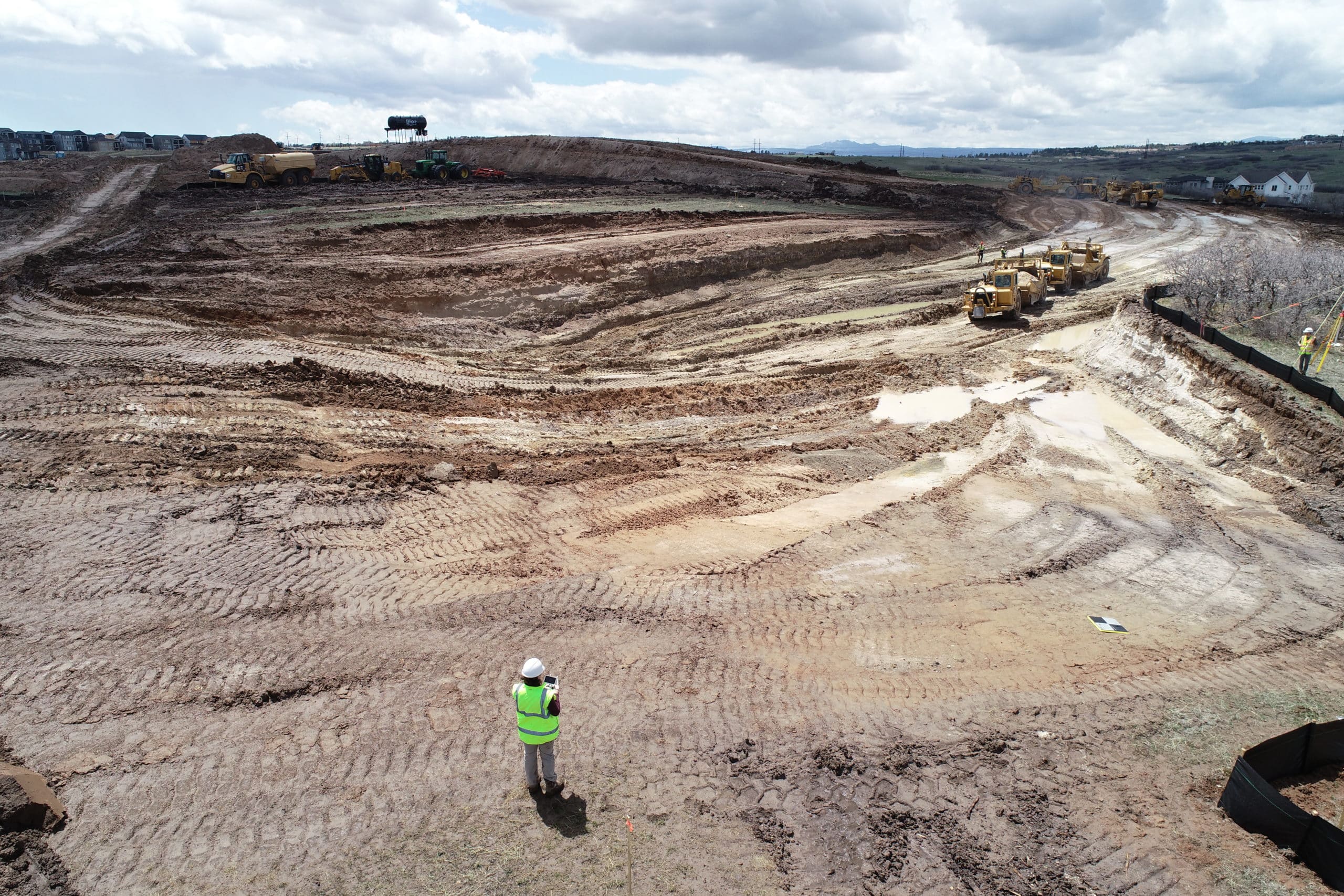 A drone pilot stood on an earthmoving site with an AeroPoint on the floor.