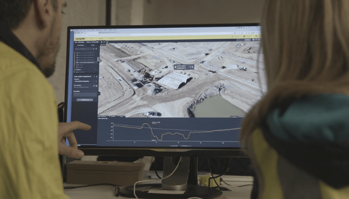 Two people looking at screen with map of a jobsite