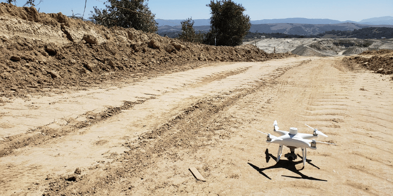 A drone sat on a dirt track ready to fly.