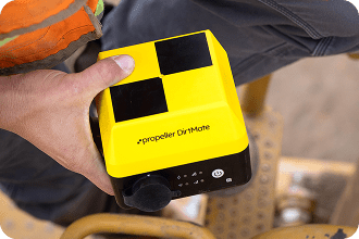 a hand holding dirtmate while climbing aboard a machine to mount as a position monitor