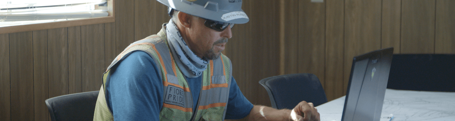 Construction worker working on a laptop in the on-site office