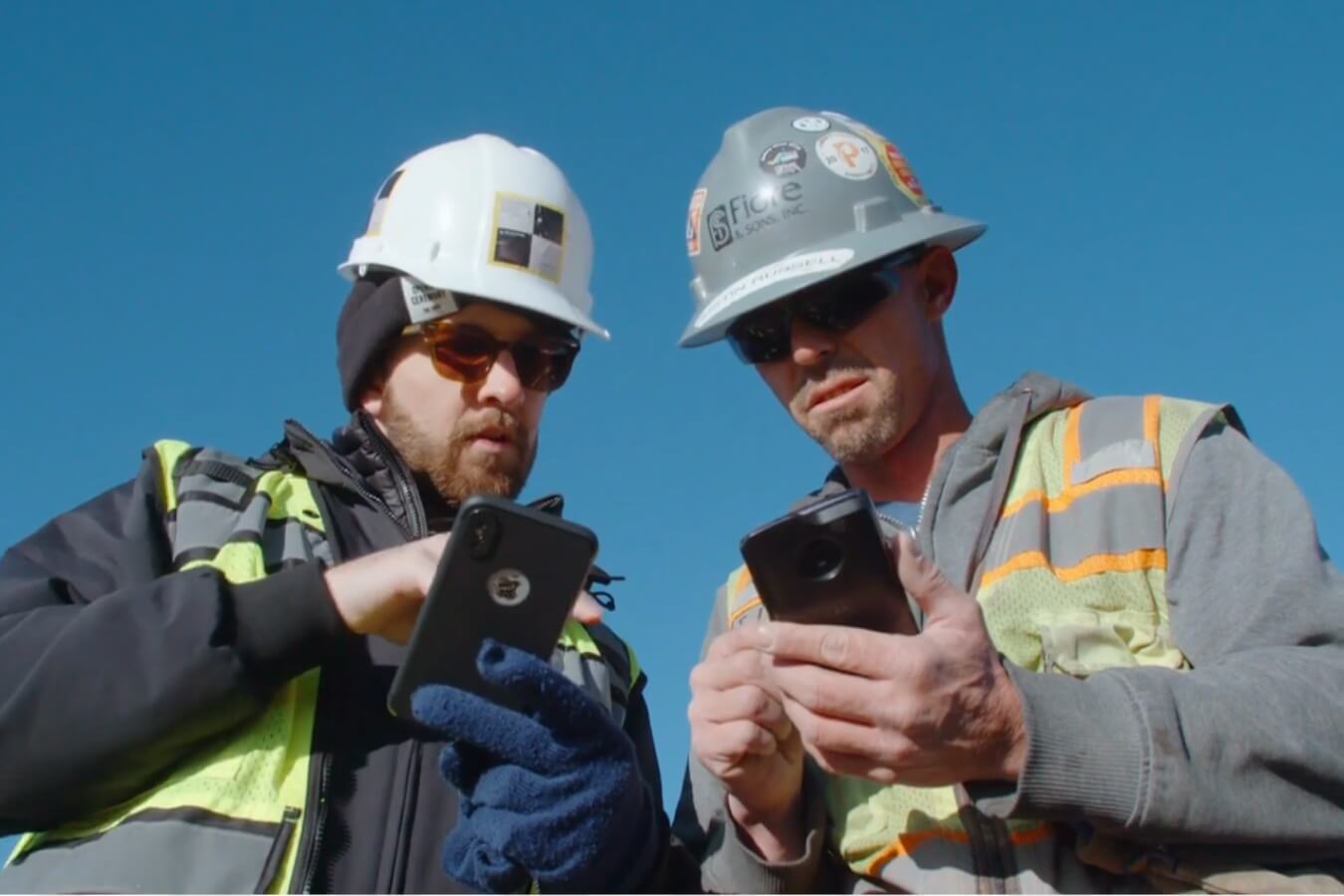 two construction workers collaborating on a mobile devices