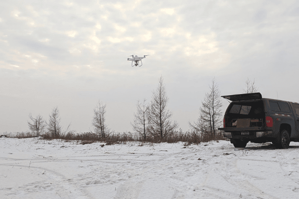 A drone in flight over snowy countryside.