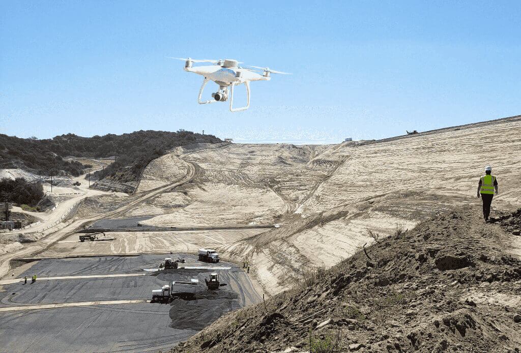 A drone flying over a waste management site with the site manager walking in the foreground. Phantom 4 RTK flying over worksite PPK workflow.