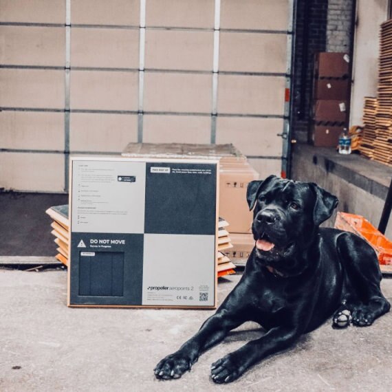 A black dog sitting nicely in front of an AeroPoint
