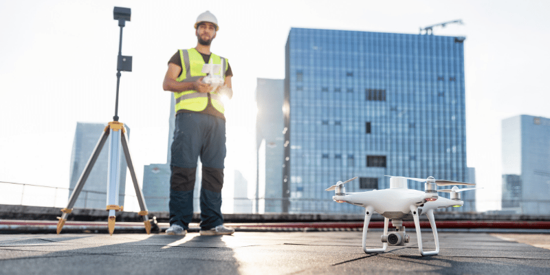 A man stood on a building's roof, about to fly a drone.
