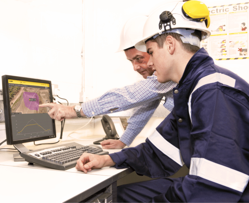 Two men in hard hats sat looking at the Propeller platform on a computer screen.