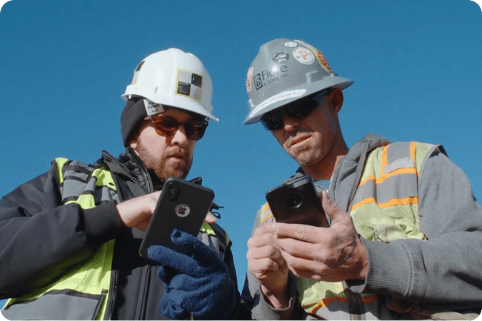 two construction workers looking at cellphones